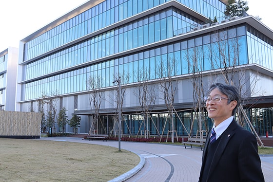 完成間近のShimadzu Tokyo Innovation Plazaを背に実はネクタイもSHIMADZUロゴ入りを着けるほど島津愛が溢れている