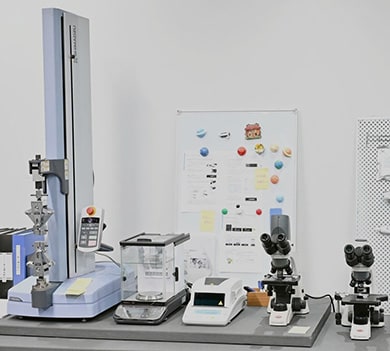 写真：（左から）スタジオに設置した小型卓上試験機 「EZ-LX HS」、分析天びん「AP225W-AD ex」、水分計「MOC63u」、島津理化製の生物顕微鏡2台
