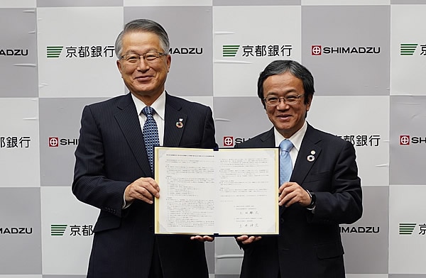 協定書を手にする京都銀行取締役頭取　土井伸宏（左）と島津製作所代表取締役社長　上田輝久（右）