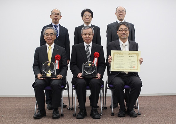 受賞盾を持つ当社代表取締役社長　山本靖則（前列左）と東北大学未来科学技術共同研究センター　須川成利教授（前列中央）