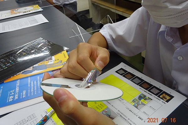 手元に送付したCD-Rを分解して調べる(学校提供写真)