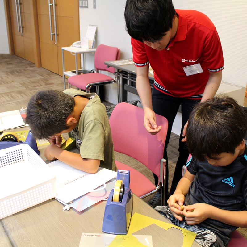 「島津ぶんせき体験スクール」でペーパークラフトを組み立てる子どもたち