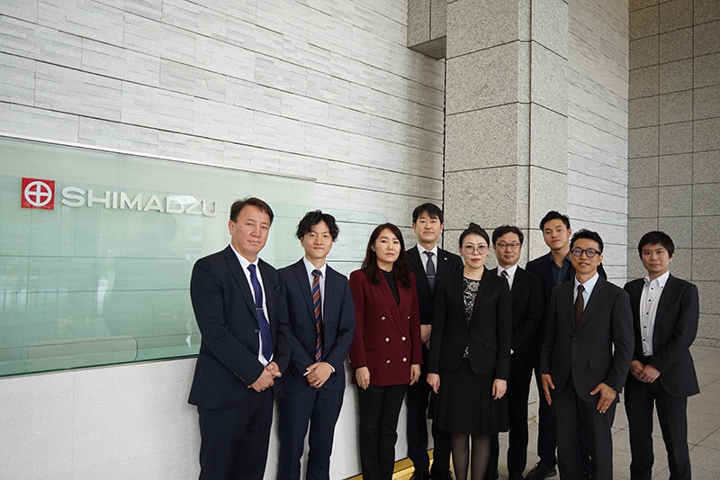 2023年4月に実施した当社本社訪問　エントランスにて（左から順にバヤムフ博士、当社海外営業部モンゴル担当 奥山主任、CIT社ゲレルマ社長、当社分析計測事業部 石橋副事業部長と当社スタッフ）