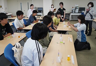 サインペンのインクの色を分ける実験で、分離分析の原理を体感。参加者は、講師の手元を注視