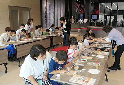 ペーパークロマトの原理で、海の生き物をかたどった用紙に色づけた。 うちわに貼って夏のアートが完成。科学って美しい!