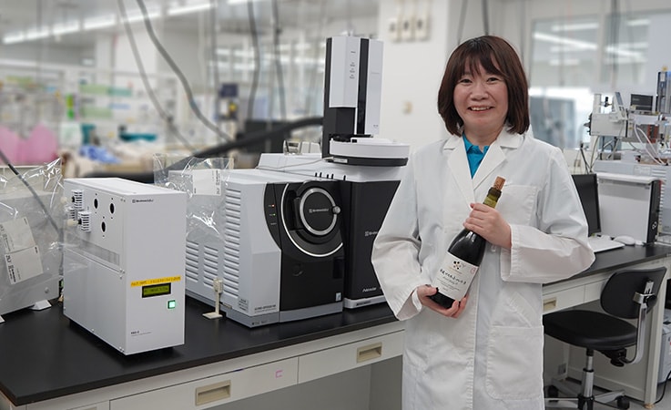 キリンホールディングス株式会社　飲料未来研究所（神奈川県・湘南アイパーク内）の佐々木佳菜子さん（コア技術研究ユニット）。中央が、香り分析に特化したガスクロマトグラフ質量分析計（GC-MS）「アロマデザイナー」