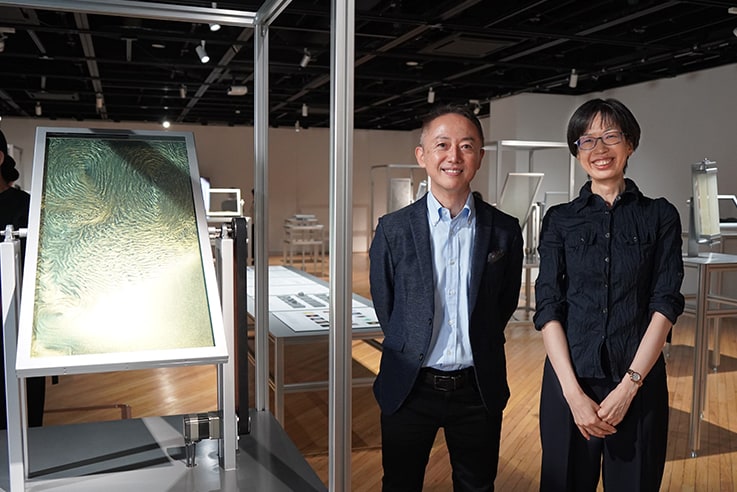 東洋アルミニウム株式会社の山崎博久さん、向井理絵さん。左の作品は同社の「クロマシャイン」を使用したもの