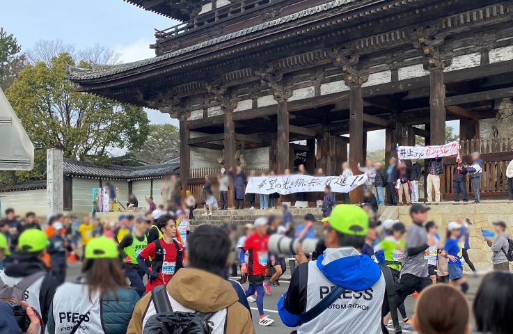 僧侶の応援を受け、島津ランナーも快走した（仁和寺門前）