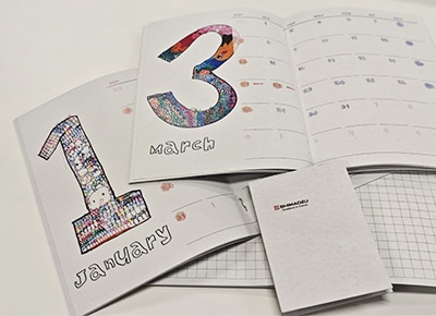 作品があしらわれたノベルティの手帳とメモ帳