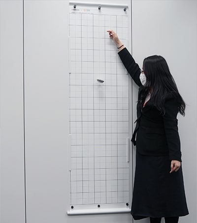 開発したスクリーンの前で使い方を説明する川崎 