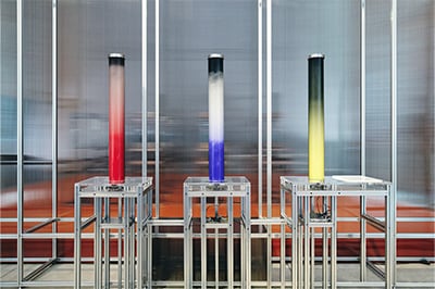「Particle Settling」台の上のボタンを押すと、2種類の岩絵具（粉末状）が筒の中で押し上げられ、混ざり合う。時間の経過とともに粉末が降下するが、重さの違いでその速度に差ができ、グラデーションが生まれる