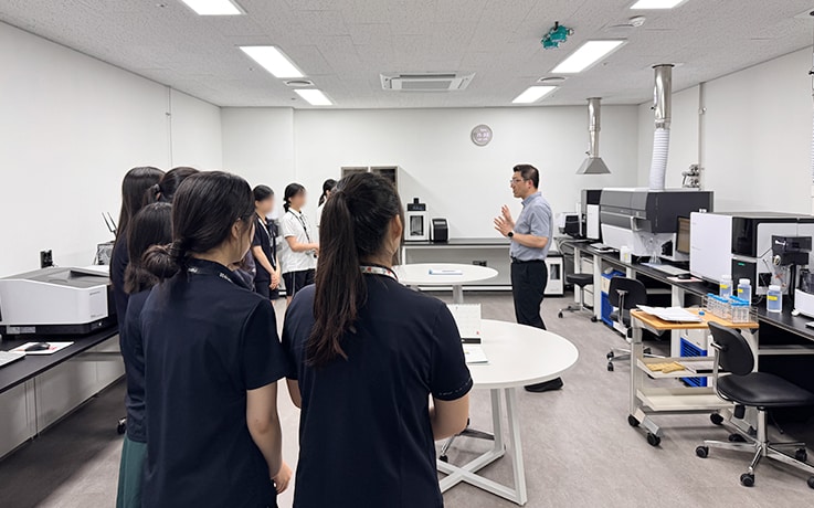 分析機器の実機を前に装置の原理を学ぶ学生たち